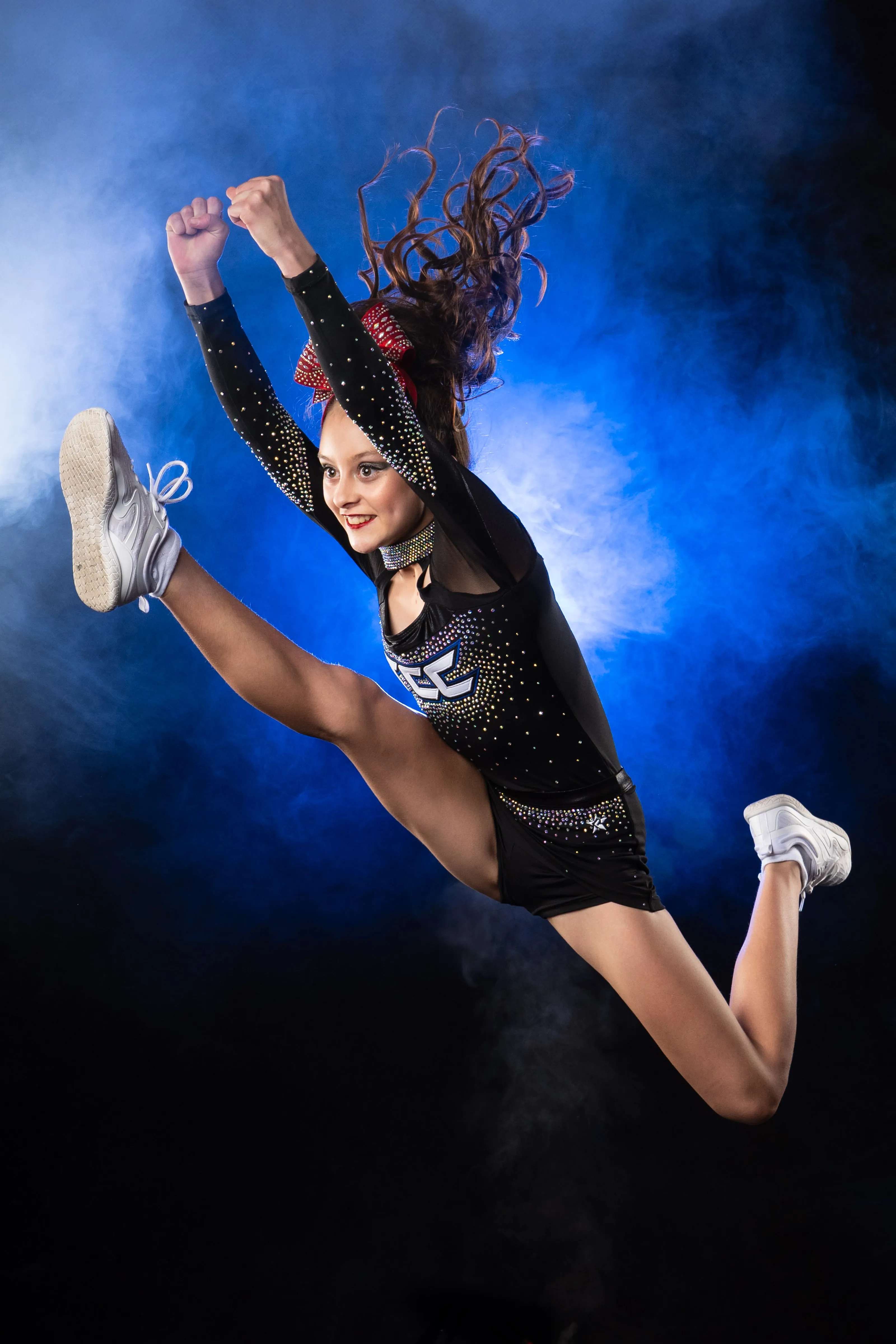 Athlete leaping through a burst of blue powder, dramatic multi-light studio sports portrait