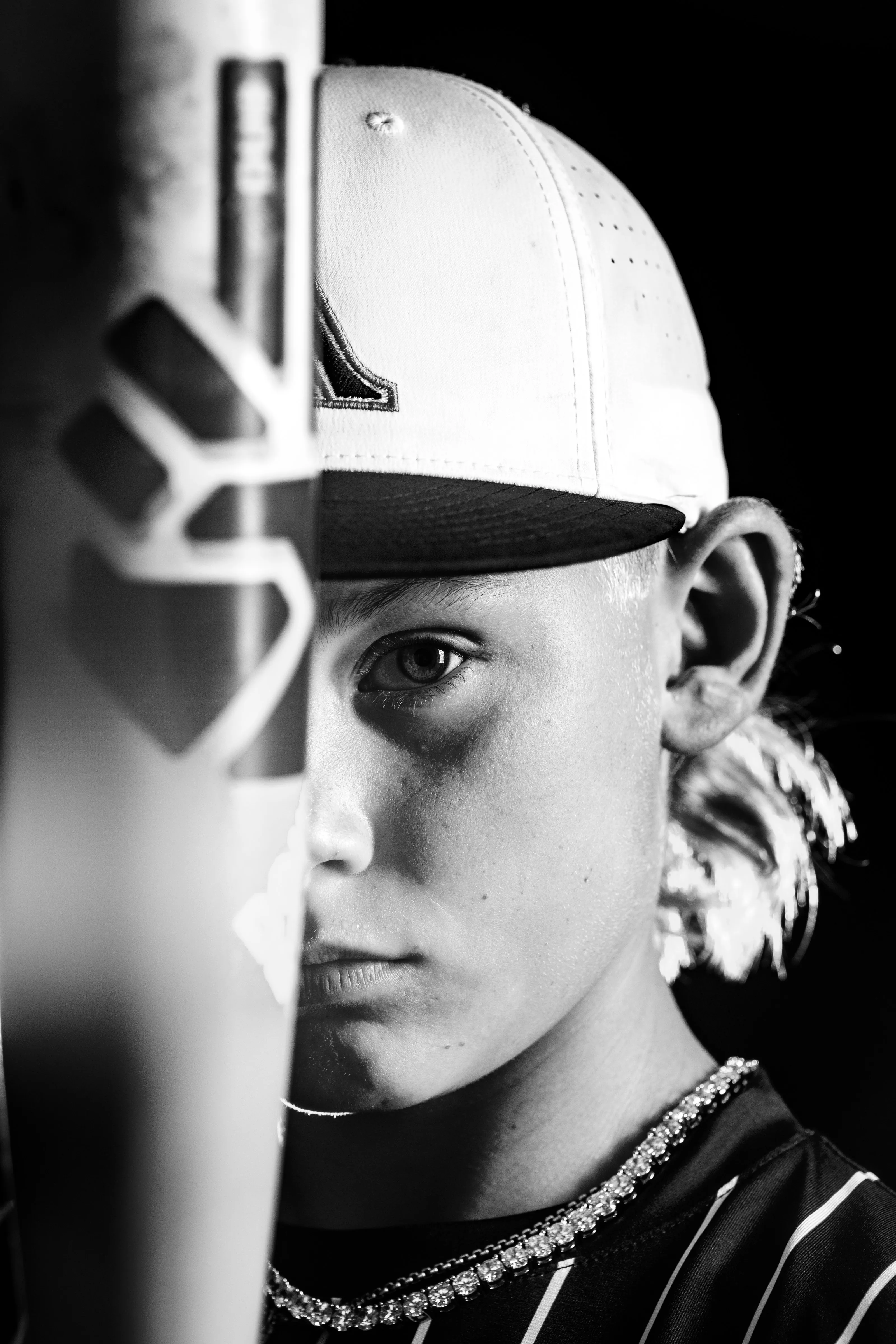 Black and white baseball portrait of a young player peering past his bat