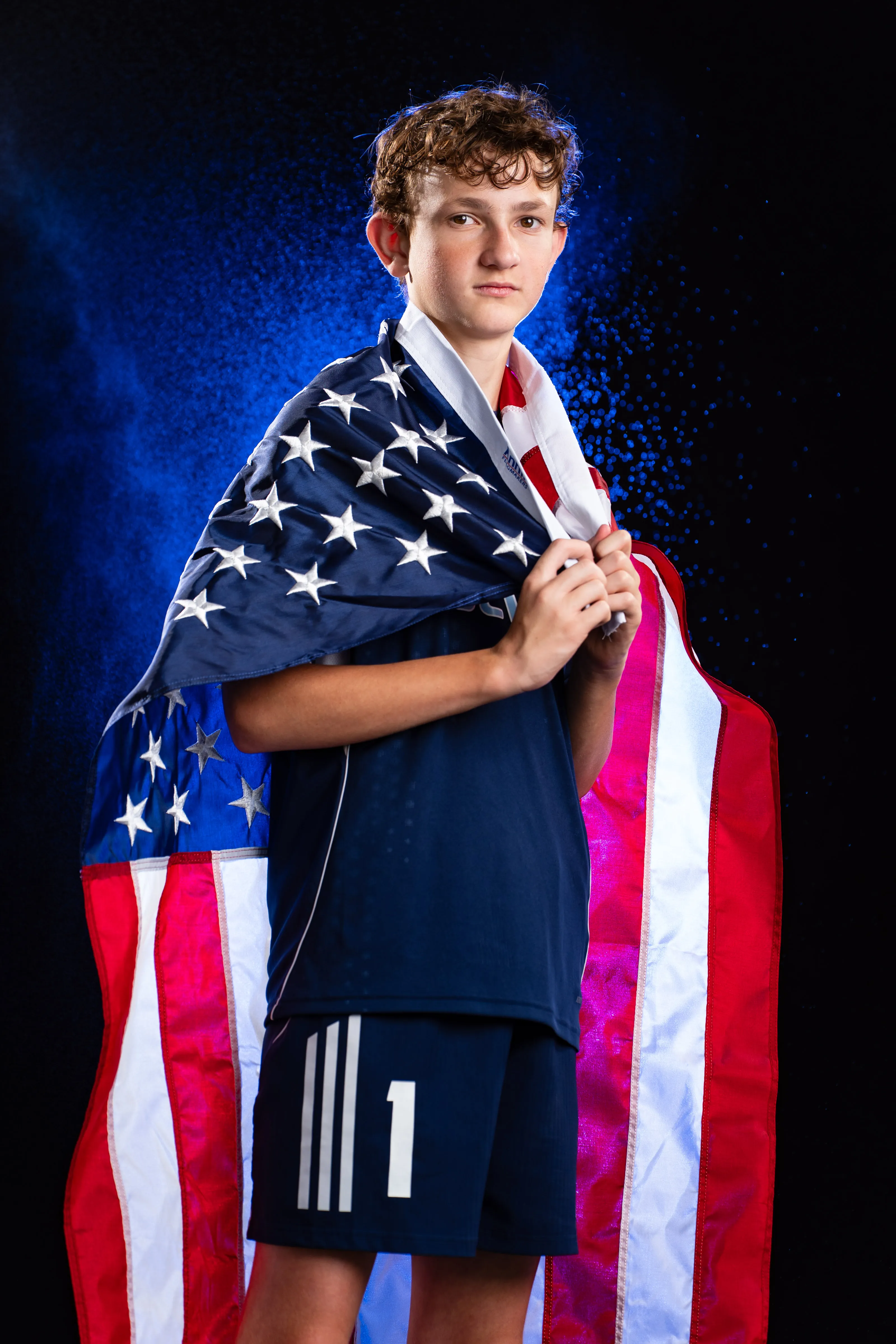 Soccer player draped in the American flag, dramatic studio portrait